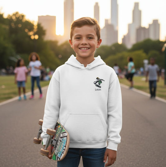 Weißer personalisierter Kinder Hoodie Skateboarder mit Namen bestickt, getragen von Junge mit Skateboard im Park. Perfekt für aktive Kids.