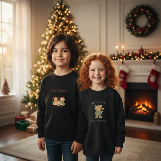 Zwei Kinder tragen das schwarze Weihnachts Sweatshirt - Bärenfamilie vor einem festlich geschmückten Weihnachtsbaum. Perfekt für festliche Familienfotos.