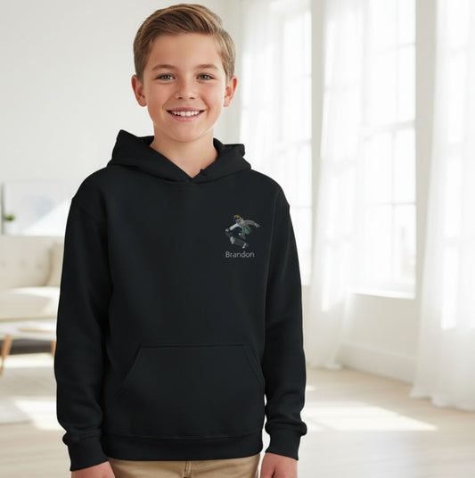 Personalisierte Kinder Hoodie Skateboarder mit Namen bestickt in Schwarz, getragen von Junge in modernem Wohnzimmer. Ideal für kleine Skater.